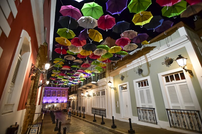 A stunning display of colorful umbrellas hanging over Calle La Fortaleza in Old San Juan, Puerto Rico, illuminated at night.